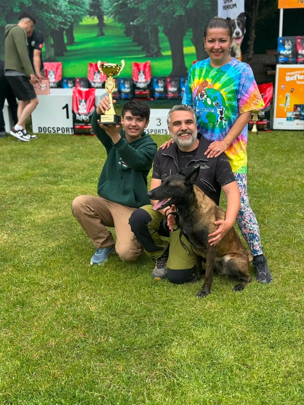 Trainer Irsat Uner with his family, his Malinois partner and the first-place trophy they won at a dog sports competition