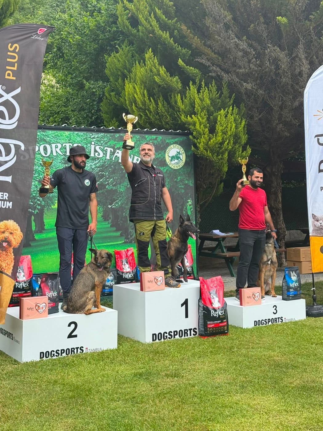 İrşat Üner ve yol arkadaşı köpeği, köpek sporları yarışmasında birincilik kürsüsünde kupasını kaldırırken